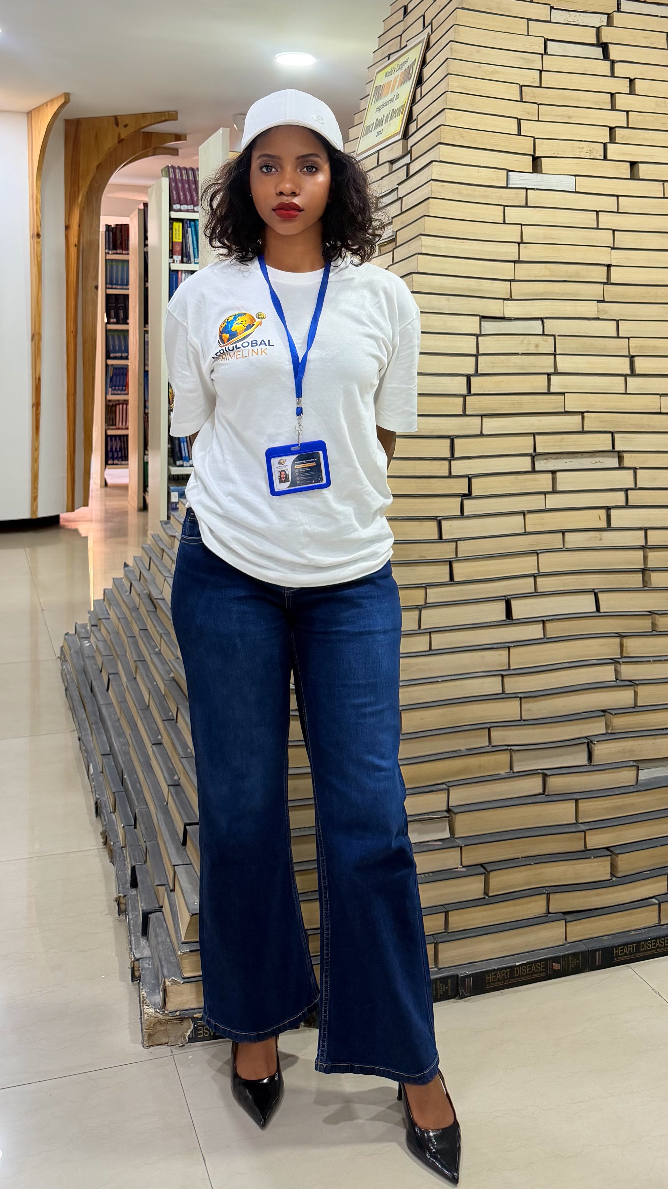 An AfriGlobal representative beside the stacked-book sculpture in the MM University library